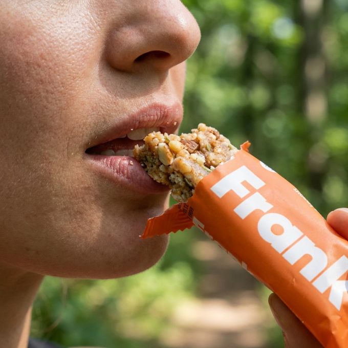 Person taking a bite of Frank protein bar