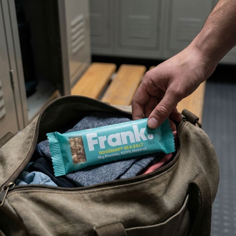 A person reaching for a Frank protein bar in a gym bag